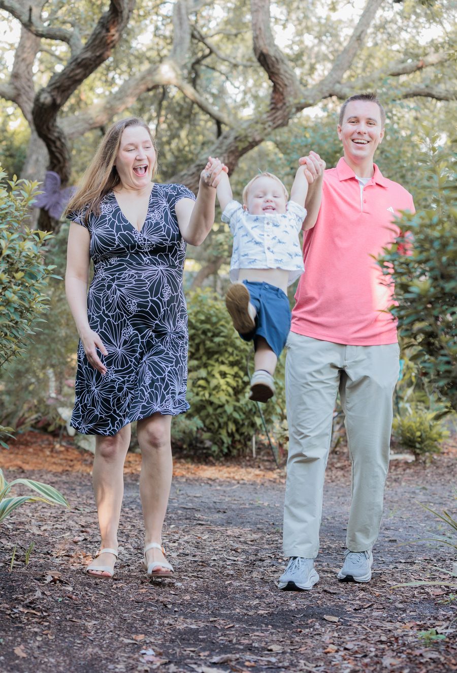 Jordan and his wife swinging their son between them on a park path